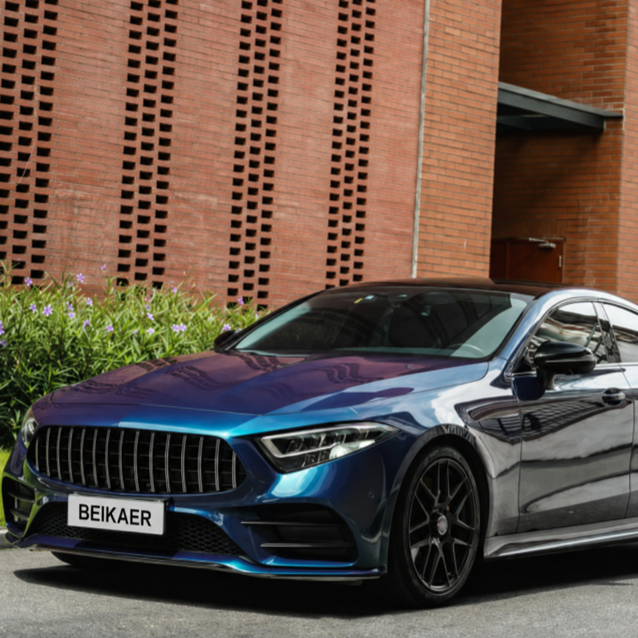 Blue and purple color shift luxury sedan with a glossy reflective wrap finish parked outdoors.